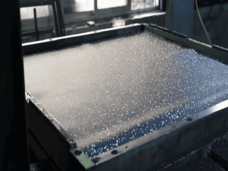Workers mixing polyurethane binder with rubber granules in factory